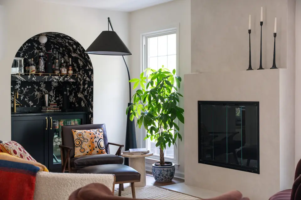 Living room with a black arched built-in, a plaster fireplace and a fiddle-leaf plant