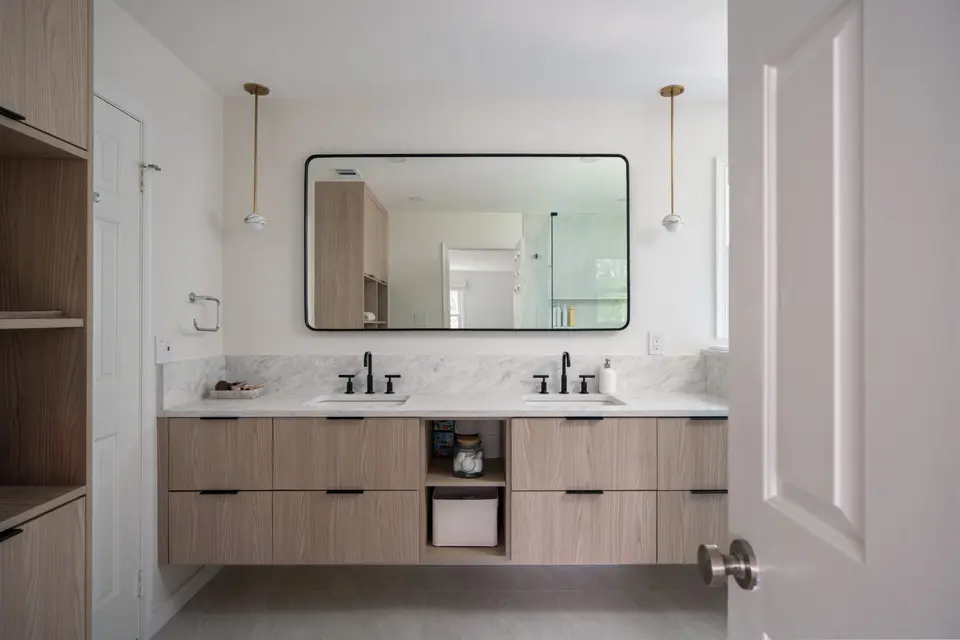 Bathroom with a floating light-oak double vanity and a black-framed mirror