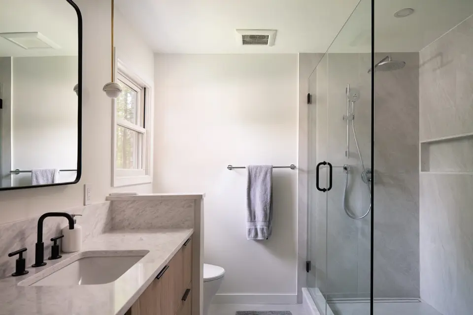 Bathroom with a glass shower, a marble vanity and black fixtures