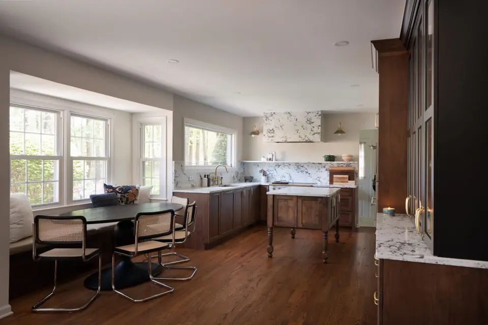 The same kitchen, wider, with a rattan-and-chrome dining set by the windows