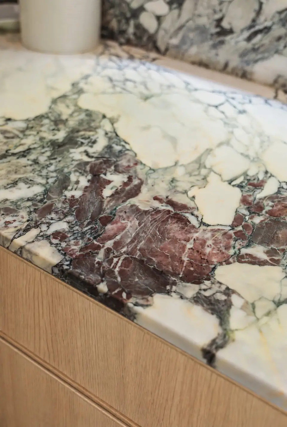 Close detail of the violet-veined marble counter edge over white oak
