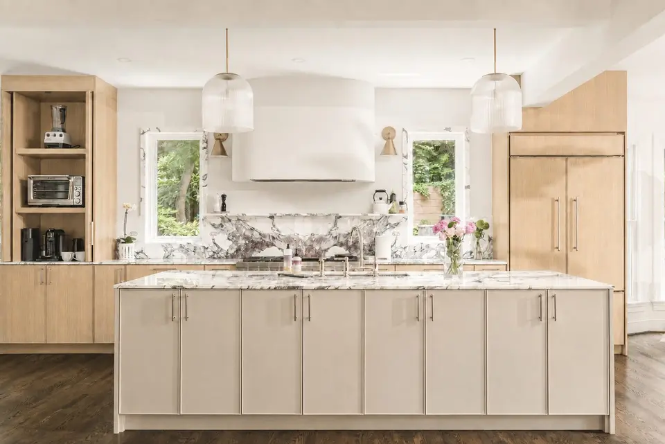 The island straight on, with glass pendants, a plaster hood and an open appliance shelf
