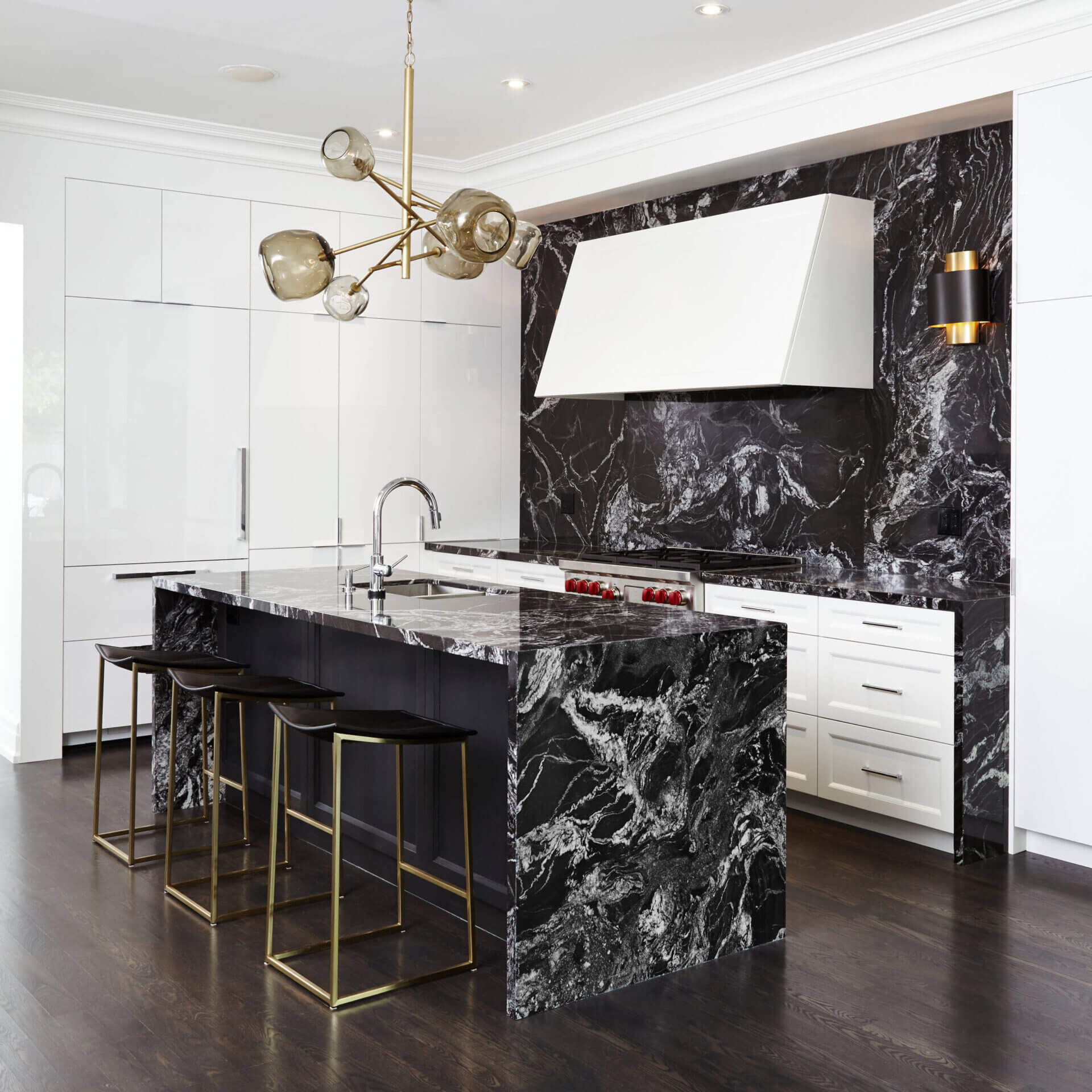 A white kitchen with a black and white marble waterfall island
